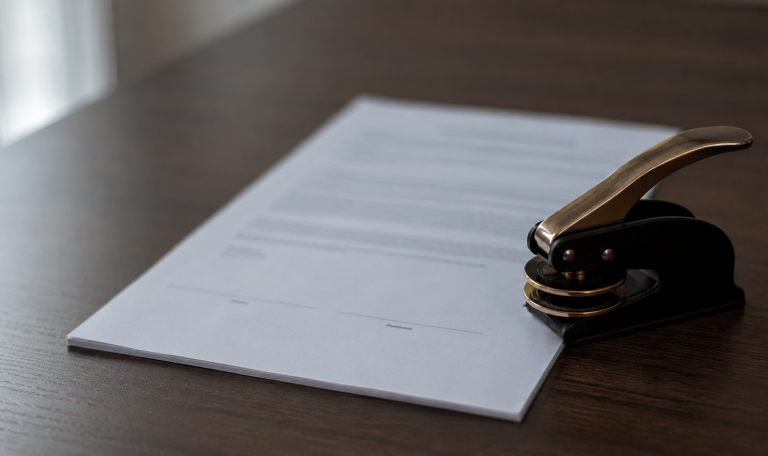 A closed notary embosser set aside beside the unsigned signature page of a commercial lease, illustrating when acknowledgment is and is not required under Washington law.